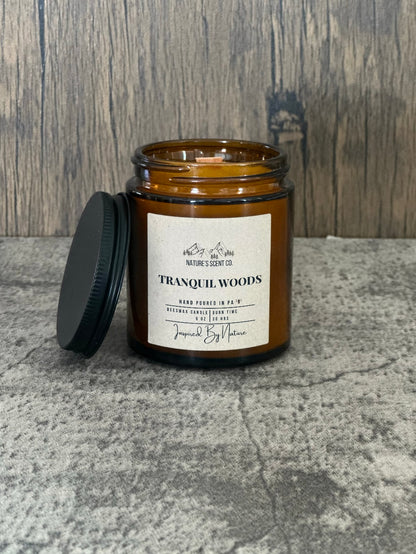 Nature inspired beeswax candle in Tranquil Woods scent with wood wick and amber jar.